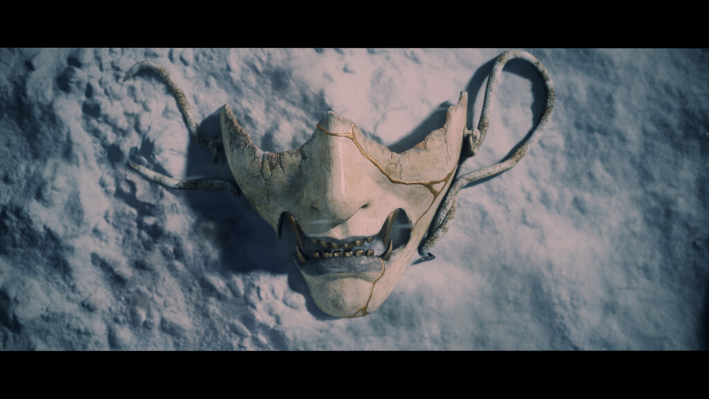 Cracked demon-like mask lying in the snow in the Ghost of Yōtei